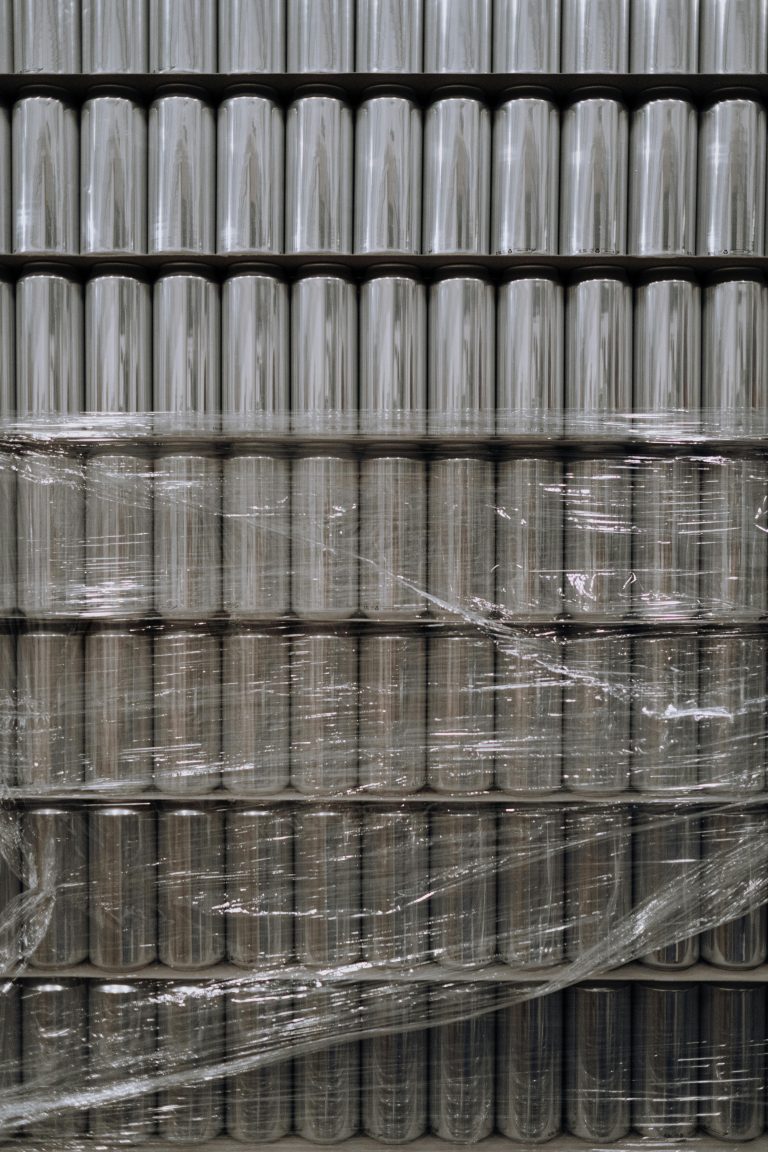 Vertical shot of stacked aluminum cans wrapped in plastic, showcasing industrial packaging.